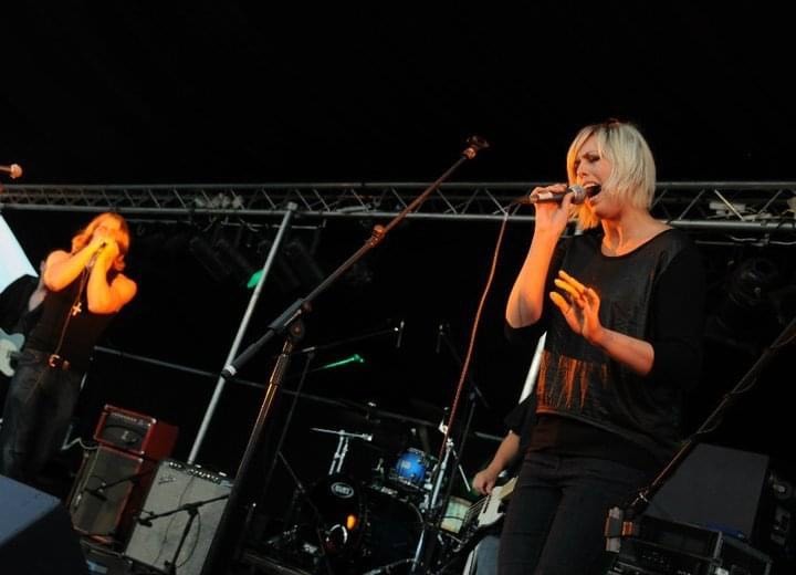 Bernii Mac performing live on stage with other musicians in the background