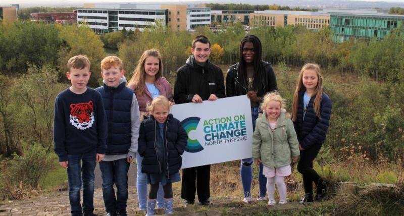 Young people in SIlverlink Biodivesity Park holding the council's new Action on Climate Change logo